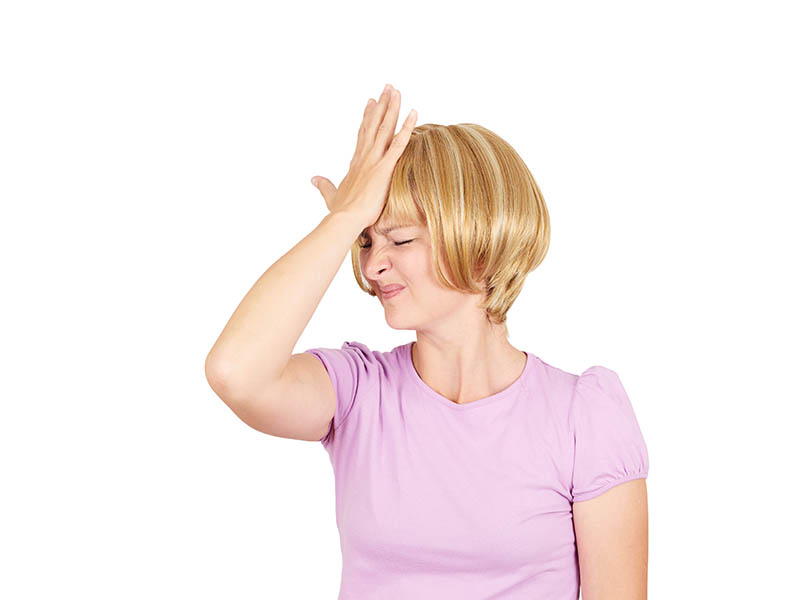 blond woman facepalming in pink shirt