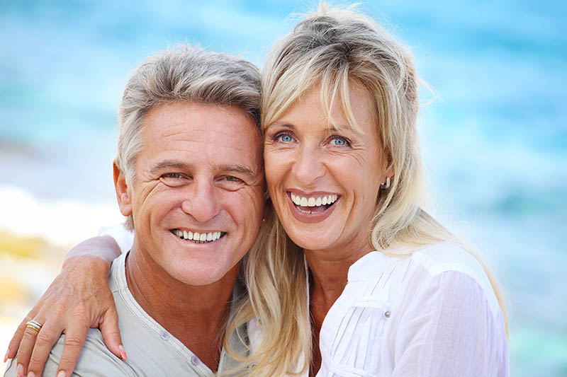 senior couple with dentures from the prosthodontist outside smiling