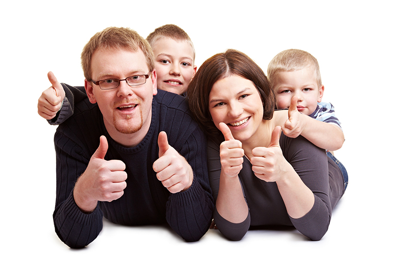 mother father and two sons laying on parents' back all giving thumbs up